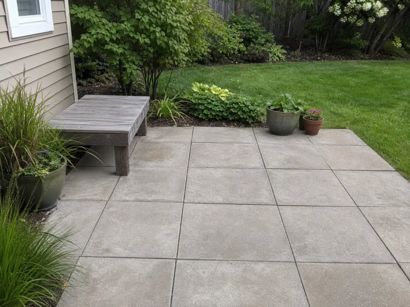 Large square patio stones installed beside a residential garden